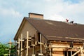 Blurred roofing construction scene with building contractors on a rooftop of a large brick house with scaffoldings