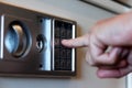 Blurred safe with combination lock and human hand in a hotel room, closeup numbers with tilt shift effect. Selective
