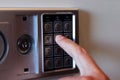 Blurred safe with combination lock and human hand in a hotel room, closeup numbers with tilt shift effect. Selective