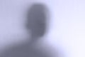 Defocused scary ghost face behind a white glass background