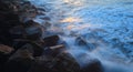 Blurred sea wave crashing over rocks Royalty Free Stock Photo