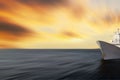 Blurred seascape with a warship at the edge of the image. Abstract motion blurred sea with sunset sky and army battleship