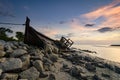 Silhouette image of abandon shipwrecked on rocky shoreline. dark cloud and soft on water Royalty Free Stock Photo