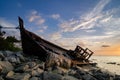 Silhouette image of abandon shipwrecked on rocky shoreline. dark cloud and soft on water Royalty Free Stock Photo