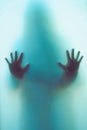 Blurred shadow of a horror woman. The hands on the glass. Dangerous person behind frosted glass. Person of mystery Halloween