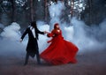 Blurred silhouette in motion of Gothic couple dancing in fog. vampire man prince in black tailcoat embraces seduces Royalty Free Stock Photo