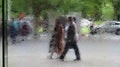 Blurred silhouette of people walking on the street. View through the glass water wall of the National Gallery of Victoria Royalty Free Stock Photo