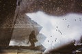 Blurred silhouette of reflection of one person walking alone on wet sidewalk of city park on rainy day. Abstract photography Royalty Free Stock Photo