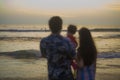 Blurred silhouette of young happy and beautiful Asian Chinese couple holding baby girl daughter enjoying sunset beach together Royalty Free Stock Photo