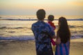Blurred silhouette of young happy and beautiful Asian Korean couple holding baby girl daughter enjoying sunset beach together Royalty Free Stock Photo