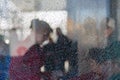Blurred silhouettes of people behind broken glass. Fine mesh of cracks. Creative background. Female profile. Bus stop.
