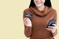Asian woman holding credit cards and cell phones for shopping online with happy, On yellow background Royalty Free Stock Photo