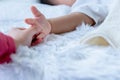 A 1 year old brother is sleeping on a white bed with an older sister holding his hand Royalty Free Stock Photo