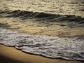 Blurred splashing sea wave on sand beach with beautiful golden sunset light reflection. Royalty Free Stock Photo