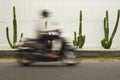 Blurred Street Motion. Scooter Biker Rides On Road Near Cactuses.