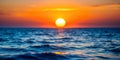 Out of focus sun setting over the ocean glowing orange with dark blue background Royalty Free Stock Photo