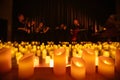 blurred symphonic orchestra on stage with lots of candles