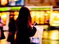 Blurred unrecognizable figure of a young girl hurrying down street in dark coat and a mobile phone in her hands. Stylized