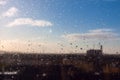 Blurred urban background with blue cloudy sky behind wet window Royalty Free Stock Photo