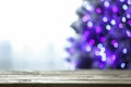 Blurred view of beautiful Christmas tree with purple lights near window indoors, focus on wooden table Royalty Free Stock Photo