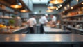 Blurred view of chefs at work in commercial eatery. Metal surface in front is for food presentation. Kitchen interior with Royalty Free Stock Photo