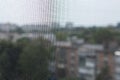 Blurred view of the city through an insect mesh on a house or apartment window