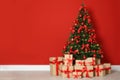 Blurred view of decorated Christmas tree and gift boxes near red wall Royalty Free Stock Photo