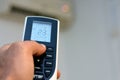 blurred view of a human hand with its thumb pressing an air conditioner remote control to turn on the air conditioning fan Royalty Free Stock Photo