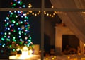 Blurred view of stylish living room interior Christmas lights and fireplace at night through window Royalty Free Stock Photo