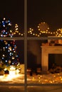 Blurred view of stylish living room interior Christmas lights and fireplace at night through window Royalty Free Stock Photo