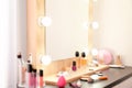 Blurred view of table with makeup products and mirror near white wall, closeup Royalty Free Stock Photo