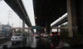 Blurred view of the traffic of car driving on road under the bridge that gets wet in the rain in city, Royalty Free Stock Photo