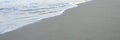 Blurred wave of the sea on the evening sand beach. banner.