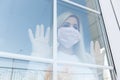 Blurred woman is behind a glass door with face mask taking self quarantine at home Royalty Free Stock Photo