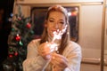 Blurred woman in knitted wool white cozy sweater hands holding sparklers bengal fire stick on the background of a camping trailer Royalty Free Stock Photo