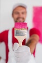 Blurred worker showing brush with paint