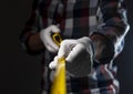 Blurred yellow retractable tape measure in hands of workman in checkered shirt, close up