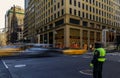 Blurred yellow taxi cabs speed past people and traffic cop at a busy crossing on 5th Avenue in Manhattan, New York, USA