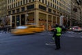 Blurred yellow taxi cabs speed past people and traffic cop at a busy crossing on 5th Avenue in Manhattan, New York, USA Royalty Free Stock Photo