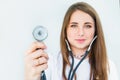 Blurred Young smiling female doctor holding her stethoscope to insinuate that it`s time for a check up in clinic on white backgro Royalty Free Stock Photo