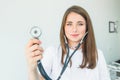 Blurred Young smiling female doctor holding her stethoscope to insinuate that it`s time for a check up in clinic on white backgro Royalty Free Stock Photo