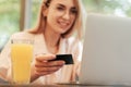 Blurred Young Smiling Woman Using Laptop for Online Shopping While Sitting in Restaurant, Blonde Girl with Glasses Royalty Free Stock Photo