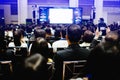 Blurry of auditorium for shareholders` meeting or seminar event with projector and white screen, many business people listening o Royalty Free Stock Photo