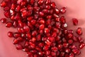 Blurry backdrop with red grains pomegranate on a pink plate.