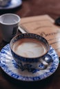 Blurry background breakfast. Cappuccino on the ceramic blue and white plate.