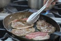 Blurry background of the chef is frying the meat in an iron pan.