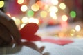 Blurry background of heart in hand. Red love shaped paper on bright colorful bokeh backgrounds. Blank paper with hope and love.