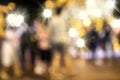 Blurry background image of defocused outdoor Christmas decorations with colorful lights and people in busy city street at night