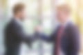 Blurry background with two businessmen shaking their hands