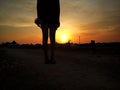 Blurry background of young girl silhouette standing alone on coutryroad against sunset view. Royalty Free Stock Photo